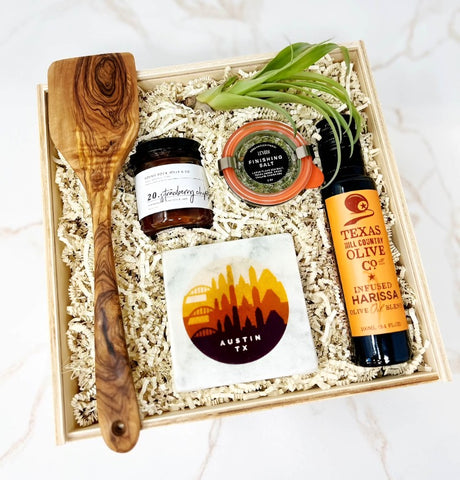 Austin Housewarming Gift Box with wooden spatula, harissa olive oil, herbed finishing salt, Austin skyline coasters, strawberry jam and an airplant