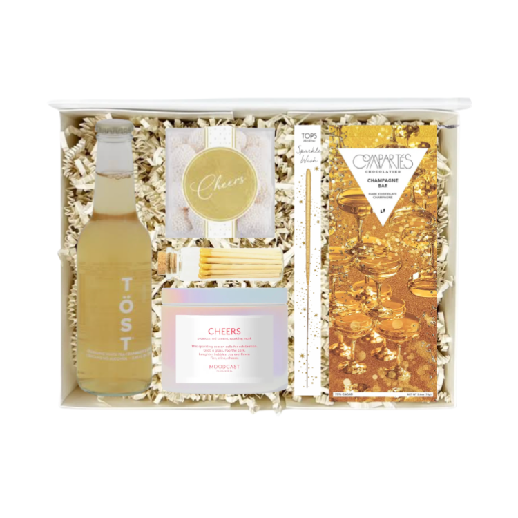 a curated new years' themed gift box filled with celebratory goodies like sparkling tea beverage, cheers sugarfina gummies, dark chocolate, sparkler wand, cheers candle and matches