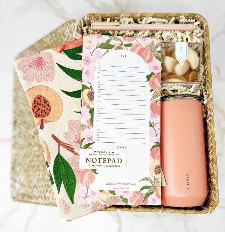 Peach Fuzz themed box with peach tea towel, market notepad, pen, peach gummies and a peach colored reusable tumbler