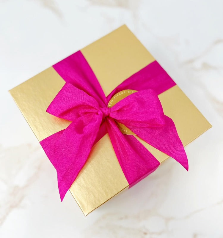 gold gift box with magenta ribbon