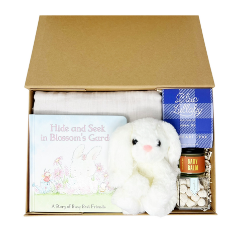 newborn baby gift box with swaddle, stuffed bunny, bunny baby book, herbal tea, baby balm and champagne flavored gummies.