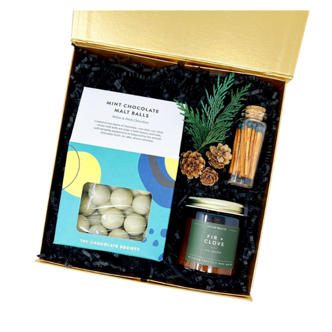 holiday gift box with peppermint chocolate malt balls, fir and clove candle and cinnamon stick matches