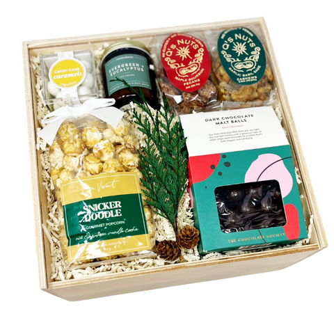 Holiday gift box with snickerdoodle popcorn, maple bourbon pecans, garlic sage cashews, peppermint bark cookie bites, peppermint malt balls, evergreen + eucalyptus candle