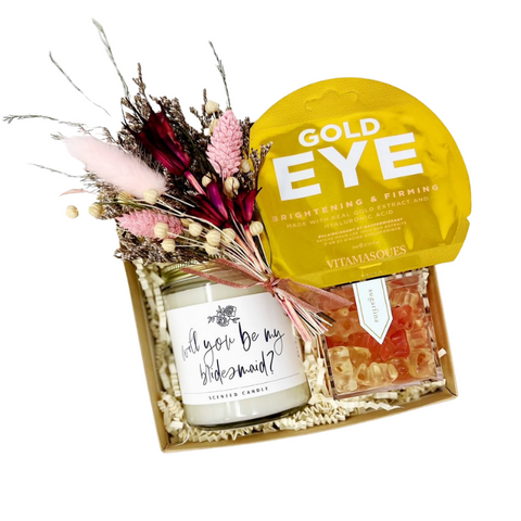 Will You Be My Bridesmaid gift box with candle that says "will you be my bridesmaid" sugarfina sparkling rosé gummy bears, gold eye firming eye gels and dried floral bundle